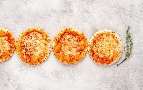 Four pizzetta Margaritas, on a light grey surface, top view