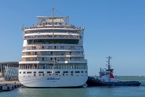 Cruise ship AIDA nova is pressed against quay wall by tugboat, Warnow, Warnemünde, Rostock,