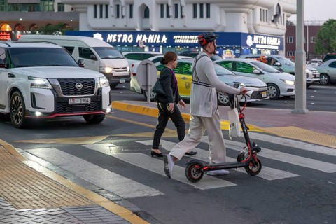 Man crossing a pedestrian crossing on an electric scooter, Abu Dhabi, United Arab Emirates
