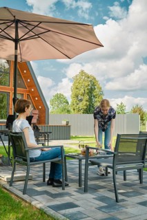 A young woman brought plates to the patio table to lay out grilled food on backyard