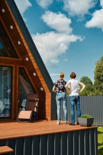 Rear view of mother and daughter standing on terrace of tiny house