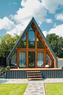 Young woman sitting on a folding chair on the terrace of a tiny house