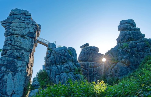 The morning sun shines through an opening in the Externsteine. The Externsteine, a sandstone rock
