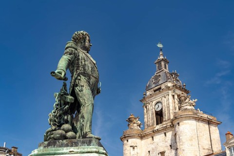Admiral Duperré statue and the Porte de la Grosse Horloge clock tower in La Rochelle, France