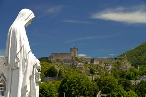 Statue on Rosary Square and the ChÃ¢teau fort de Lourdes fortress in the Marian pilgrimage town of