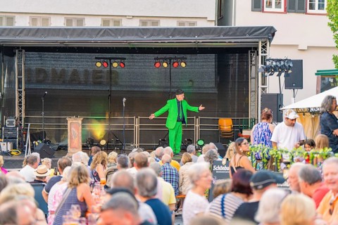 An entertainer on a stage entertains a large audience at an evening event, 950 years Weil der Stadt