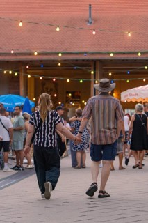 A couple holding hands and walking through a lively evening event, 950 years Weil der Stadt