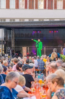 A man in a green suit stands on a stage and speaks to a large crowd, 950 years Weil der Stadt