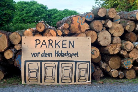 Parking regulations for cars, handwritten and hand-drawn parking sign in front of a woodpile,