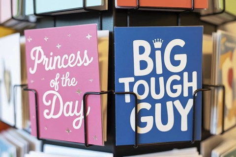 Stereotypical pink and blue birthday greeting cards for children on a rack. Societal expectations