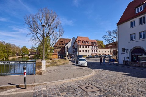 General architecture, street, cobblestone pavement, parking lane with vehicles, metal railing,