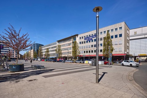 Square, lantern, modern architecture, trees, parking lane with vehicles, alleyway sign, blue sky,