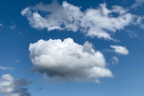 White clouds below altocumulus above ripping stratocumulus in front of blue sky. international