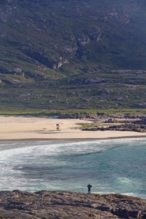 A picturesque beach with clear waters, surrounded by rocky cliffs and rolling hills, Outer