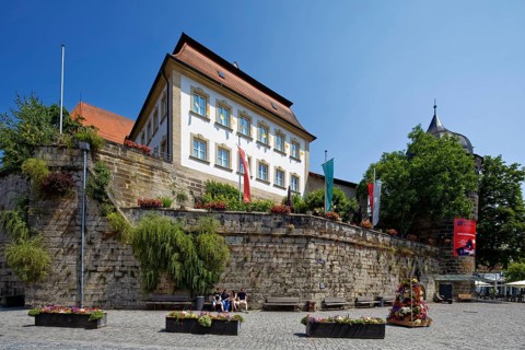 Marienplatz cobbled, flower pots, town wall, above catholic parish office St. Johannes, on the