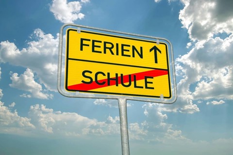 (Photomontage) Symbolic image summer holidays: Town exit sign with text HOLIDAYS and SCHOOL