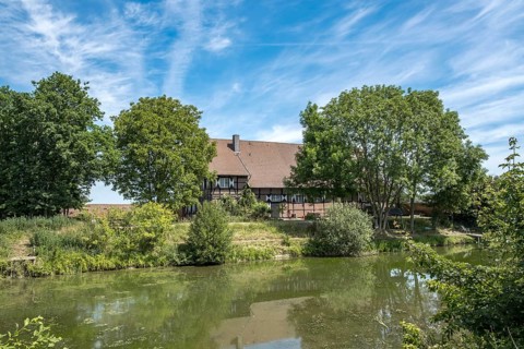 A house on the banks of the river Stever, surrounded by trees under a blue sky, MÃ¼nsterland, North