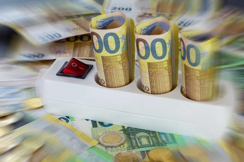 Symbolic image of electricity costs: multiple socket outlet with euro banknotes and euro coins