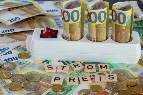 Symbolic image of electricity costs: multiple socket with euro banknotes and euro coins, with the