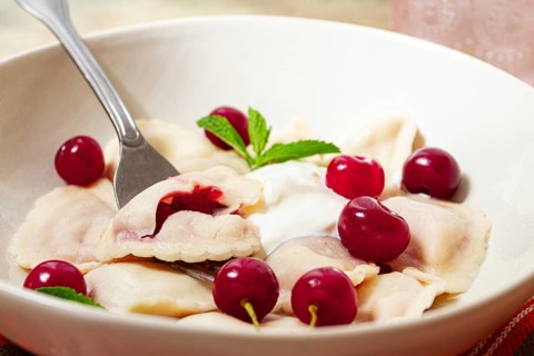 Traditional dumplings with cherries and yogurt, close-up, no people