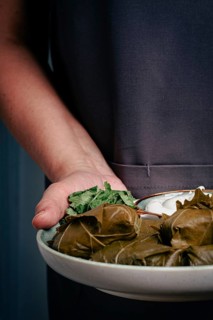 A man holds a plate in his hands, a dolma with sauce and lemon