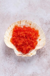 Orange flying fish roe, Tobiko roe, in a seashell, top view