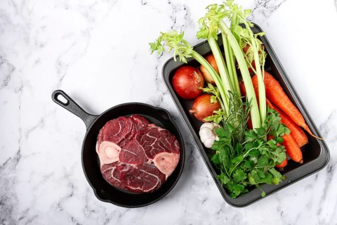 Sknuckle on the bone, raw meat for ossobuco, in a cast-iron pan, baking sheet with vegetables, top