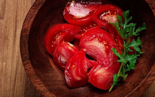 Sliced tomato, on a wooden plate, tomato salad, food background, no people