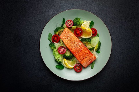 Grilled salmon fillet, with vegetables, broccoli, cherry, iceberg lettuce, spices and herbs,