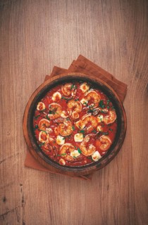 Saganaki with shrimp, in a clay pan, Greek dish, shrimp in tomato sauce, feta cheese, homemade, no