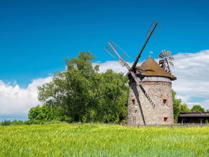 Old windmill behind a fence in a green field in spring, tower windmill, Endorf, Saxony-Anhalt,