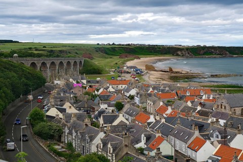 Coastal town with a viaduct and orange tiled roofs under a cloudy sky, Portsoy, Aberdeenshire,