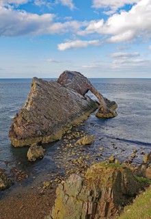 Remarkable rock formation jutting into the sea under a blue sky with few clouds, Bow Fiddle Rock,