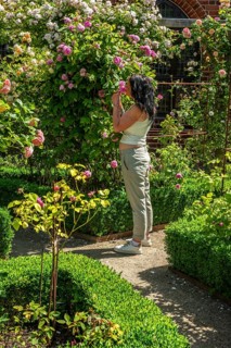 Full-length young woman smelling roses in Ystad monastery garden, SkÃ¥ne County, Sweden,