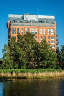 Newly (2025) built apartment building rising above the trees and behind a pond in Ystad, SkÃ¥ne