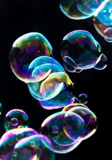 Iridescent soap bubbles in the colours of the rainbow against a black background, Recklinghausen,