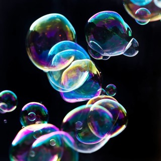 Iridescent soap bubbles in the colours of the rainbow against a black background, Recklinghausen,