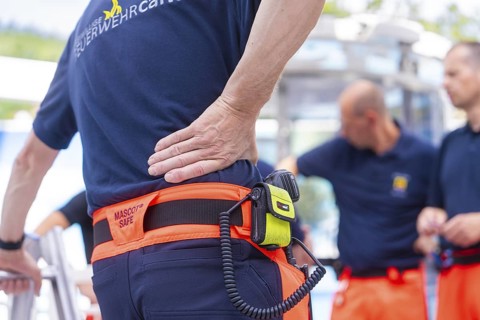 Firefighters in uniform talk to each other, one wears a radio on his belt, fire brigade exercise