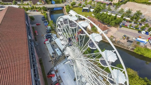 View from above of a Ferris wheel next to a river and buildings, fire brigade exercise for gondola