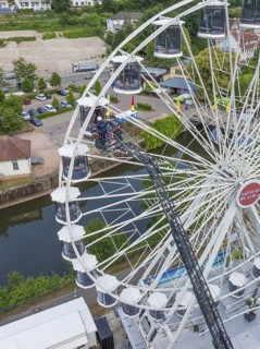 Workers working on a Ferris wheel near a river and building, fire brigade exercise for gondola