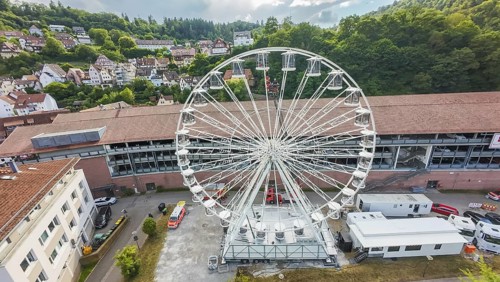 Urban landscape with a central Ferris wheel surrounded by trees, fire brigade exercise for gondola