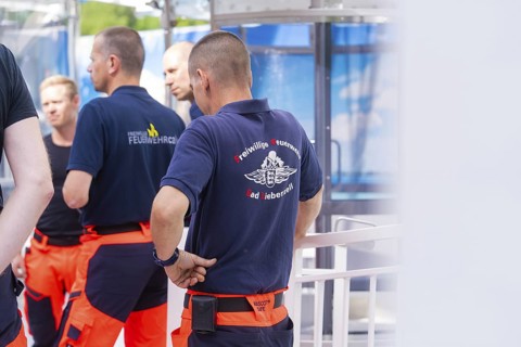 Firefighters in blue and orange uniforms stand together and talk, Fire brigade exercise for gondola