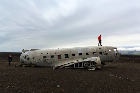 Tourist on aircraft wreckage, US Navy Douglas DC-3 transport plane, Sander, volcanic landscape,