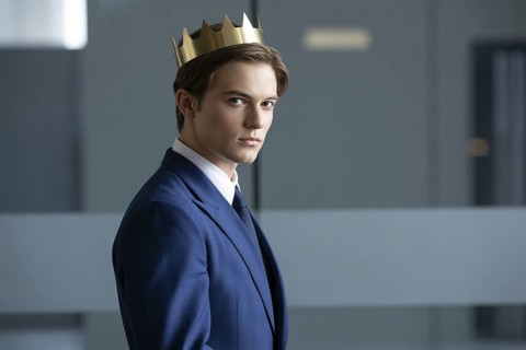 Young man in suit wearing golden crown. Studio portrait symbolizes quiet male authority and the