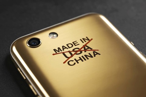 Close-up of Made in USA text crossed out and replaced with China on back of shiny golden smartphone