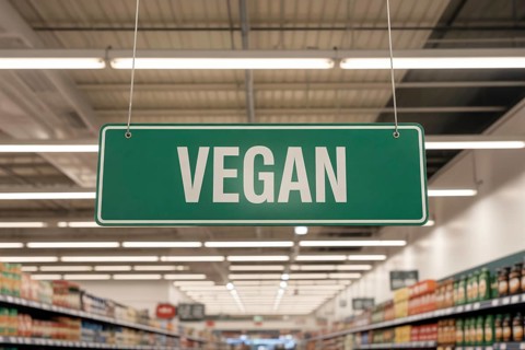 Green VEGAN ceiling sign marks location of plant-based foods in modern supermarket aisle.