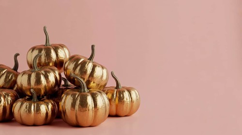 Metallic golden mini pumpkins arranged on pink background. Autumn harvest decoration banner with