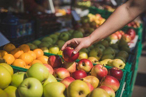 Hand reaching for fresh apples at a farmers market. Concept for healthy seasonal eating and