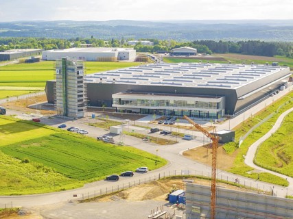 Large modern warehouse in the middle of green fields under a cloudy sky, industrial area, Nagold, I
