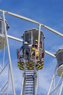 Rescue workers help a person in a giant wheel cabin, fire brigade exercise for gondola rescue,